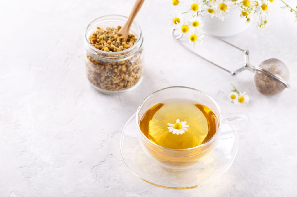 a cup of chamomile tea with fresh chamomile flowers