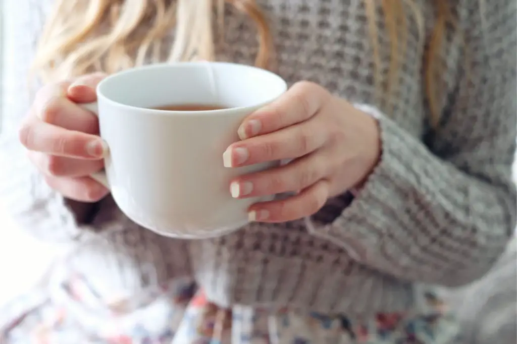 girl with a hot cup of white tea using a tea bag